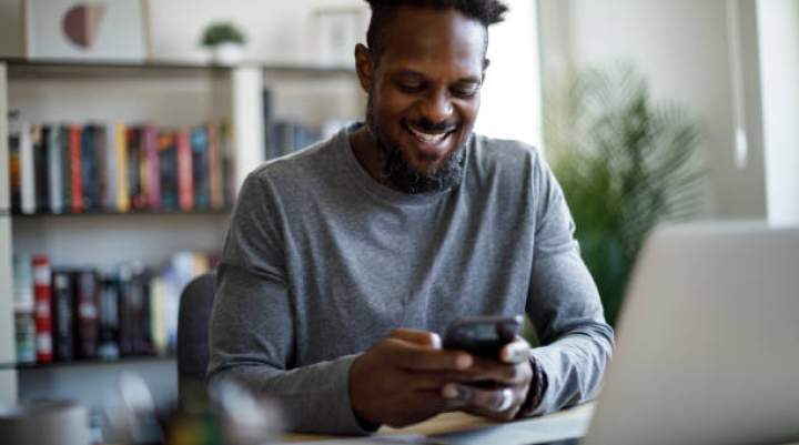 Image of a man smiling at his phone 