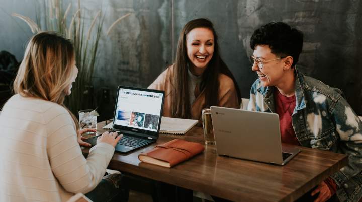 People sit at a table with laptops 