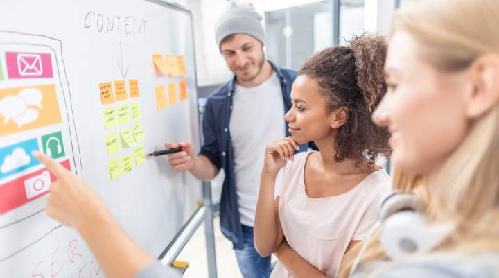 People with sticky notes on a whiteboard