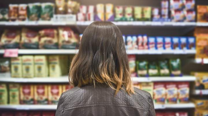 A woman stood in a supermarket aisle looking at brands