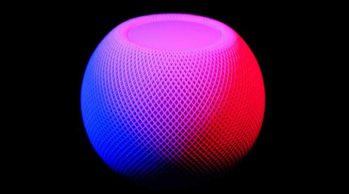 A picture of a smart speaker glowing red and purple against a black background