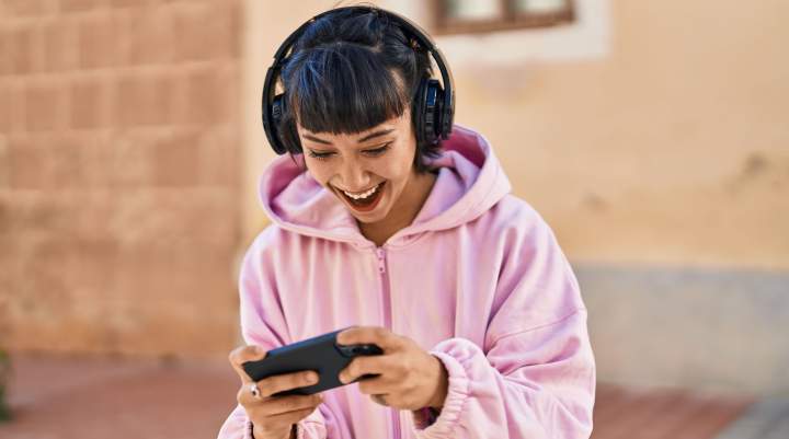 A woman happily gaming on her smartphone.