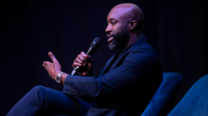 Man holding a mic while sitting in a chair 